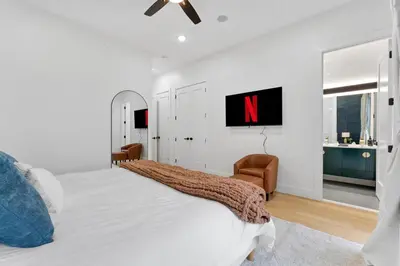 a white bedroom with a large bed and a chair at Luxury 3BR Backyard Oasis Close to NYC FirePit in Jersey City