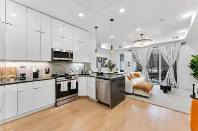 a kitchen with white cabinets and a living room at Luxury 3BR Backyard Oasis Close to NYC FirePit in Jersey City