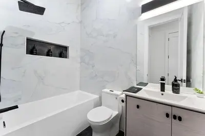 a white bathroom with a tub and a toilet and a sink at Luxury 3BR Backyard Oasis Close to NYC FirePit in Jersey City