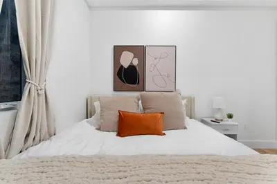 a bedroom with a white bed with an orange pillow at Luxury 3BR Backyard Oasis Close to NYC FirePit in Jersey City