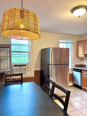 a kitchen with a table and a stainless steel refrigerator at Ten Minute Commute to NYC in Jersey City