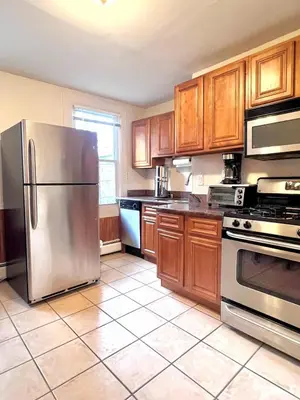 a kitchen with wooden cabinets and a stainless steel refrigerator at Ten Minute Commute to NYC in Jersey City