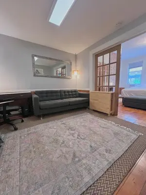 a living room with a couch and a mirror at Ten Minute Commute to NYC in Jersey City