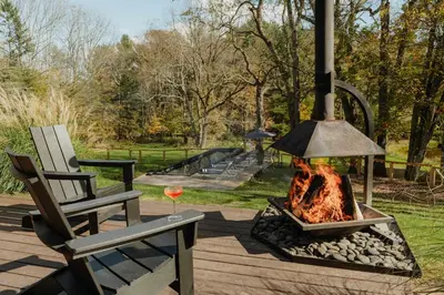 a fire pit next to a chair and a glass of wine at Coop 002 in Kenoza Lake