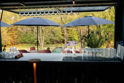 a table with chairs and umbrellas in front of a pool at Coop 002 in Kenoza Lake