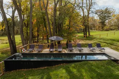 a pool with chairs and an umbrella in a yard at Coop 004 in Kenoza Lake