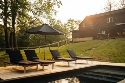 a group of chairs and an umbrella next to a pool at Coop 004 in Kenoza Lake