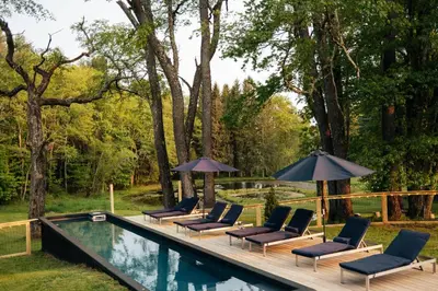 a group of chairs and umbrellas next to a pool at FOUNDERS COTTAGE - 2 room with kitchennete in Kenoza Lake