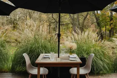 a wooden table with two chairs and an umbrella at FOUNDERS COTTAGE - 2 room with kitchennete in Kenoza Lake