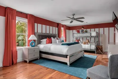 a bedroom with red walls and a bed with a child on it at The Poconest - Luxurious Mountain Mansion in Long Pond
