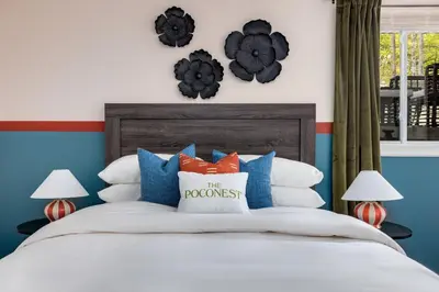 a bedroom with a bed with blue and white pillows at The Poconest - Luxurious Mountain Mansion in Long Pond