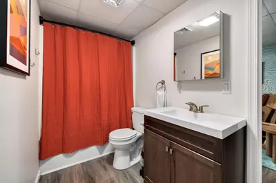 a bathroom with a toilet sink and a red shower curtain at The Poconest - Luxurious Mountain Mansion in Long Pond