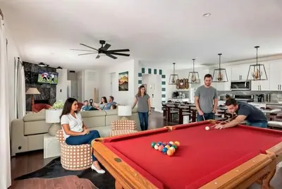 a group of people in a living room with a pool table at The Poconest - Luxurious Mountain Mansion in Long Pond