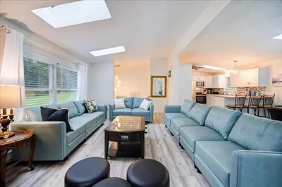 a living room with blue couches and a kitchen at Catskills Lakefront with Hot Tub, Sauna and Theater in Monticello