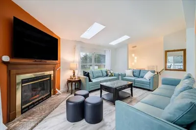 a living room with blue couches and a fireplace at Catskills Lakefront with Hot Tub, Sauna and Theater in Monticello