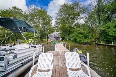 a dock with chairs and a boat on the water at Catskills Lakefront with Hot Tub, Sauna and Theater in Monticello