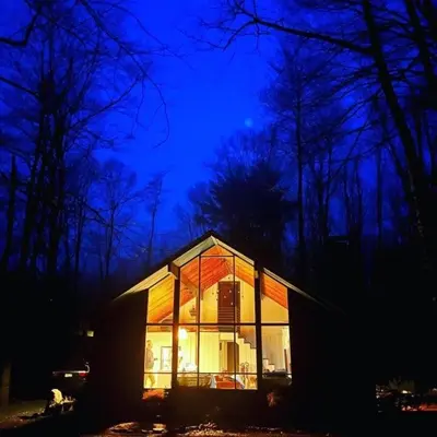 a small house with glass windows at night at Cozy Cottage 1 Block Walk From Lake Naomi - Poconos Pennsylvania Area 2 hours from New York City or Philadelphia - Pets Welcome - Check Minimum Night Requirement in Pocono Pines