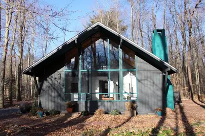 a small house in the middle of a forest at Cozy Cottage 1 Block Walk From Lake Naomi - Poconos Pennsylvania Area 2 hours from New York City or Philadelphia - Pets Welcome - Check Minimum Night Requirement in Pocono Pines