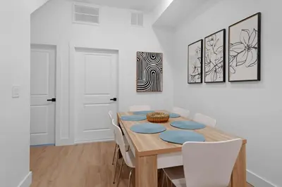 a dining room with a wooden table and white chairs at Luxury Duplex in Hoboken 15Min to NYC, Fire Pit in Jersey City