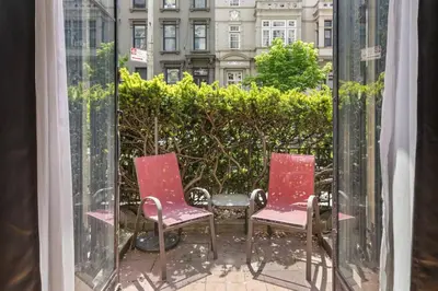 two red chairs sitting on a patio outside a window at Stylish Studio in Central Park Best Location Ever in New York