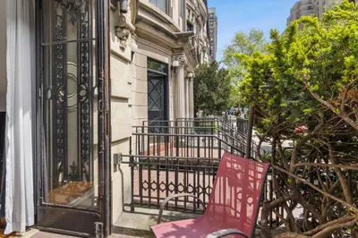 a red chair sitting on the balcony of a house at Stylish Studio in Central Park Best Location Ever in New York