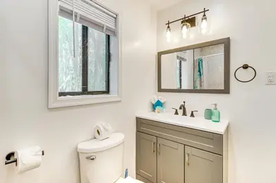 a bathroom with a toilet and a sink and a mirror at Poconos Family Home with Lake Access and Game Room in Tobyhanna