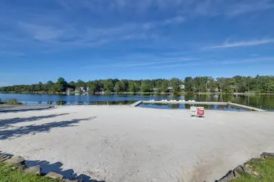 a sandy beach next to a body of water at Poconos Family Home with Lake Access and Game Room in Tobyhanna