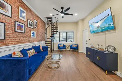 a living room with a blue couch and a brick wall at Free Parking -NEW 3BR-2Bath, 5 Beds, 10 Min to NYC, Sleeps 7 in Hoboken