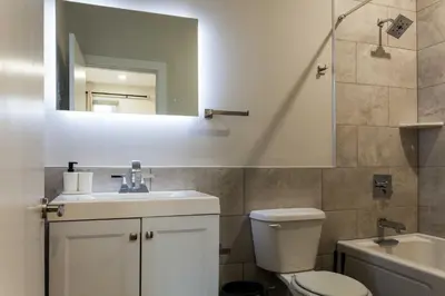 a bathroom with a toilet and a sink and a mirror at 4Bedrm,4Bath-BackyardWiFi WDCoffeeParking in Philadelphia