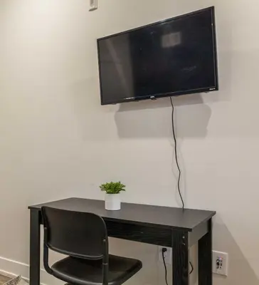 a desk with a chair and a television on a wall at 4Bedrm,4Bath-BackyardWiFi WDCoffeeParking in Philadelphia