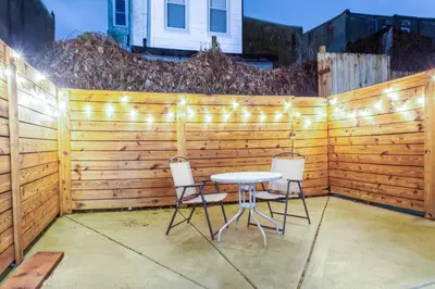a patio with a table and chairs in front of a wooden fence at 4Bedrm,4Bath-BackyardWiFi WDCoffeeParking in Philadelphia