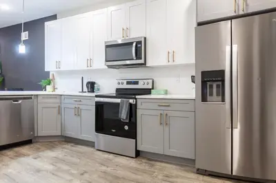 a kitchen with white cabinets and stainless steel appliances at 4BR4Bath Home WiFi WD Ping Pong in Philadelphia