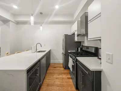 a kitchen with stainless steel appliances and wooden floors at Apartmint at Liberty B - Philadelphia in Philadelphia