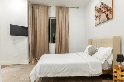 a bedroom with a white bed and a television at Central Philly 2BR2BAWiFi WDSleeps 4-6 in Philadelphia