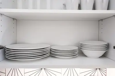 three plates and bowls on a shelf in a kitchen at 1BDRM & AptWifi near TrendyEateriesBrewerytown in Philadelphia