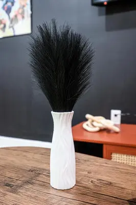 a white vase with black feathers in it on a table at Chill in Style Anime Themed Escape in Philadelphia