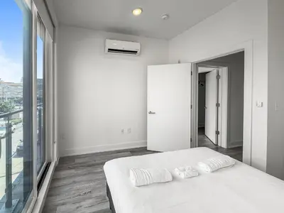 a white bedroom with a bed and a large window at Apartmint at Liberty C - Philadelphia in Philadelphia
