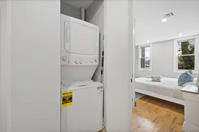 a kitchen with a refrigerator and a bedroom with a bed at Luxury and Chic 2BR 2BA Apt Mins to NYC and Hoboken in Jersey City