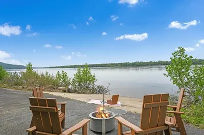 two chairs and a table with a fire in front of a lake at The Boat House Water Views Sunsets in York