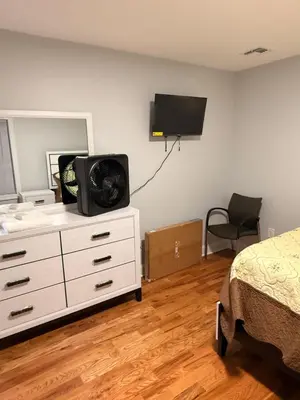 a bedroom with a bed and a dresser with a tv on the wall at Excel homes in East Orange