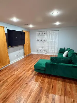 a living room with a green couch and a flat screen tv at Excel homes in East Orange