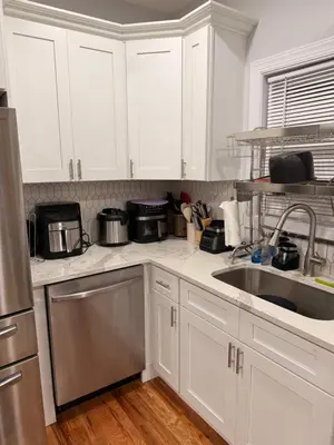 a kitchen with white cabinets and a sink at Excel homes in East Orange