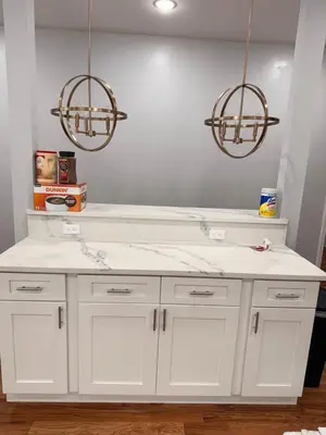 a kitchen with a white counter and two chandeliers at Excel homes in East Orange