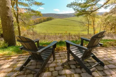two chairs sitting on a patio with a view of a field at Charming Little House at Buckleberry View EV Recharge Gorgeous View Hot Tub in Spring Mills
