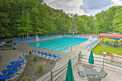 a large swimming pool with blue chairs and tables at Less Than 2 Mi to Big Bass Lake Modern Mtn Chalet! in Gouldsboro