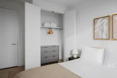 a white bedroom with a white bed and a closet at Blueground Jersey City EV charging nr park NYC-1690 in New York