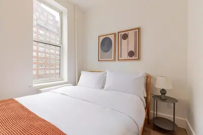 a white bedroom with a bed and a window at Blueground Manhattan wd AC nr park NYC-1829 in New York