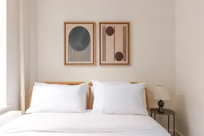 two beds in a bedroom with two pictures on the wall at Blueground Manhattan wd AC nr park NYC-1829 in New York
