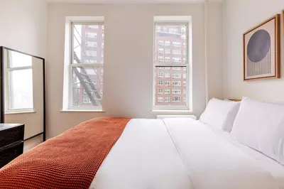 a bedroom with a large white bed with two windows at Blueground Manhattan wd AC nr park NYC-1829 in New York