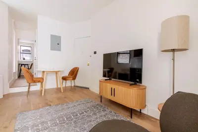 a living room with a television and a table and chairs at Blueground Manhattan wd AC nr park NYC-1829 in New York